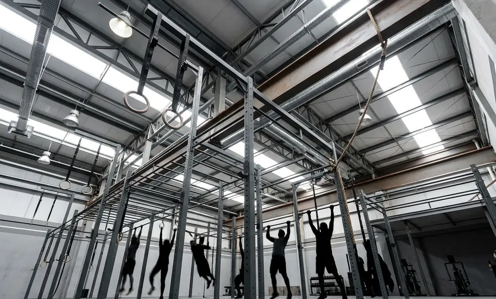 Rig de CrossFit multi-estação com corda e anéis suspensos em galpão metálico de pé direito 6 metros